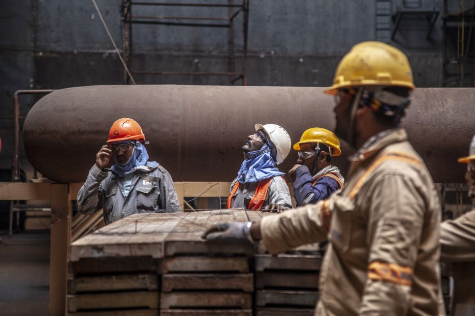 Offshore and maritime workers alongside heavy yard infrastructure.